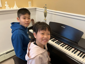 A child and child sitting at a piano